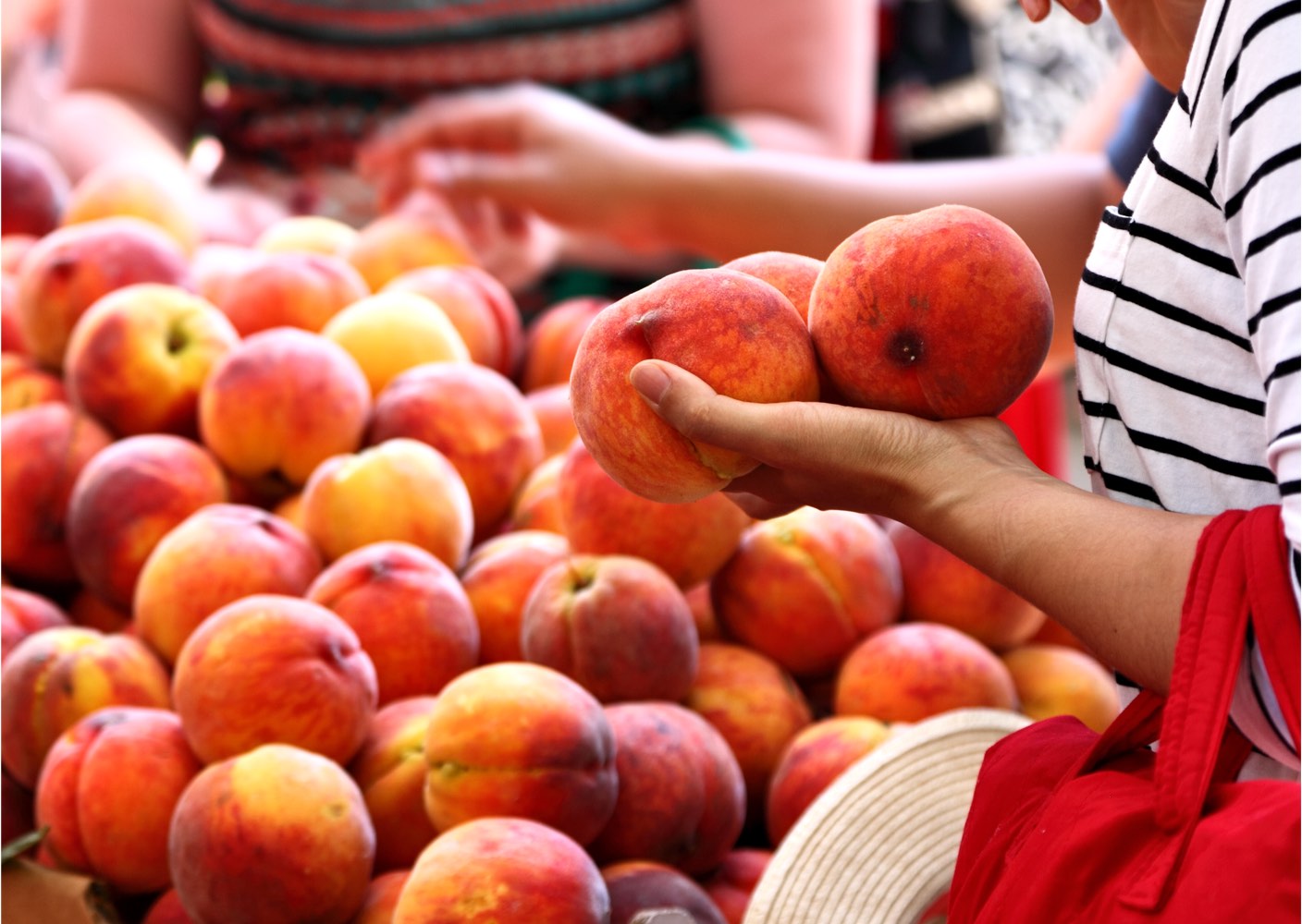 Eine Frau kauft frische Pfirsiche am Wochenmarkt